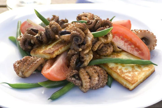 Chargrilled Octopus And Haloumi Salad on a white plate.