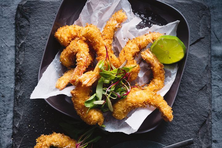 Coconut Crumbed Prawns With Lime Aioli on a black platter.