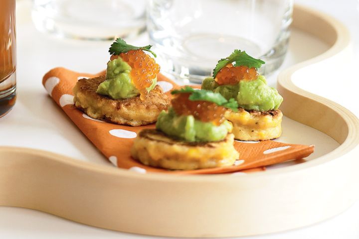 Corn Blini With Avocado And Salmon Roe on wooden platter.