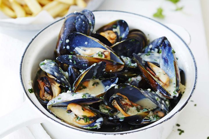 Creamy Garlic Mussels With Chips in a white bowl.