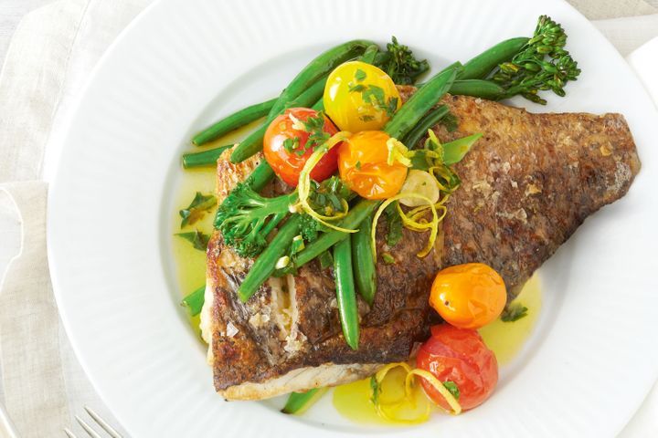 Crispy Skinned Barramundi With Garlic And Herb Oil displayed on white plate.