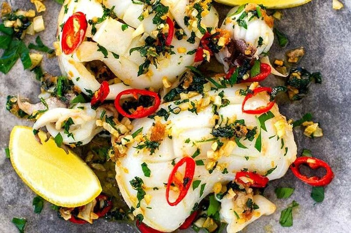 Grilled Squid With Garlic, Chili And Parsley on a plate.