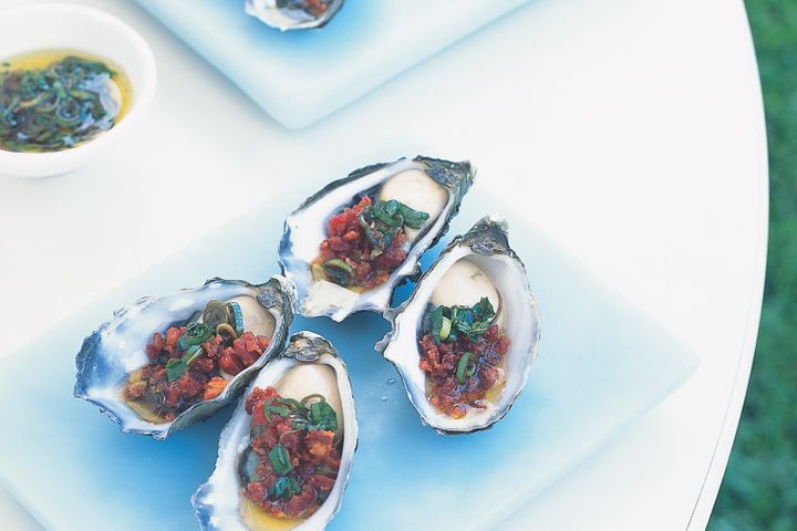 Oysters With Chorizo And Basil Dressing on white platter.