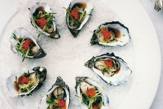 Oysters With Japanese Dressing on sea salt on a white plate.