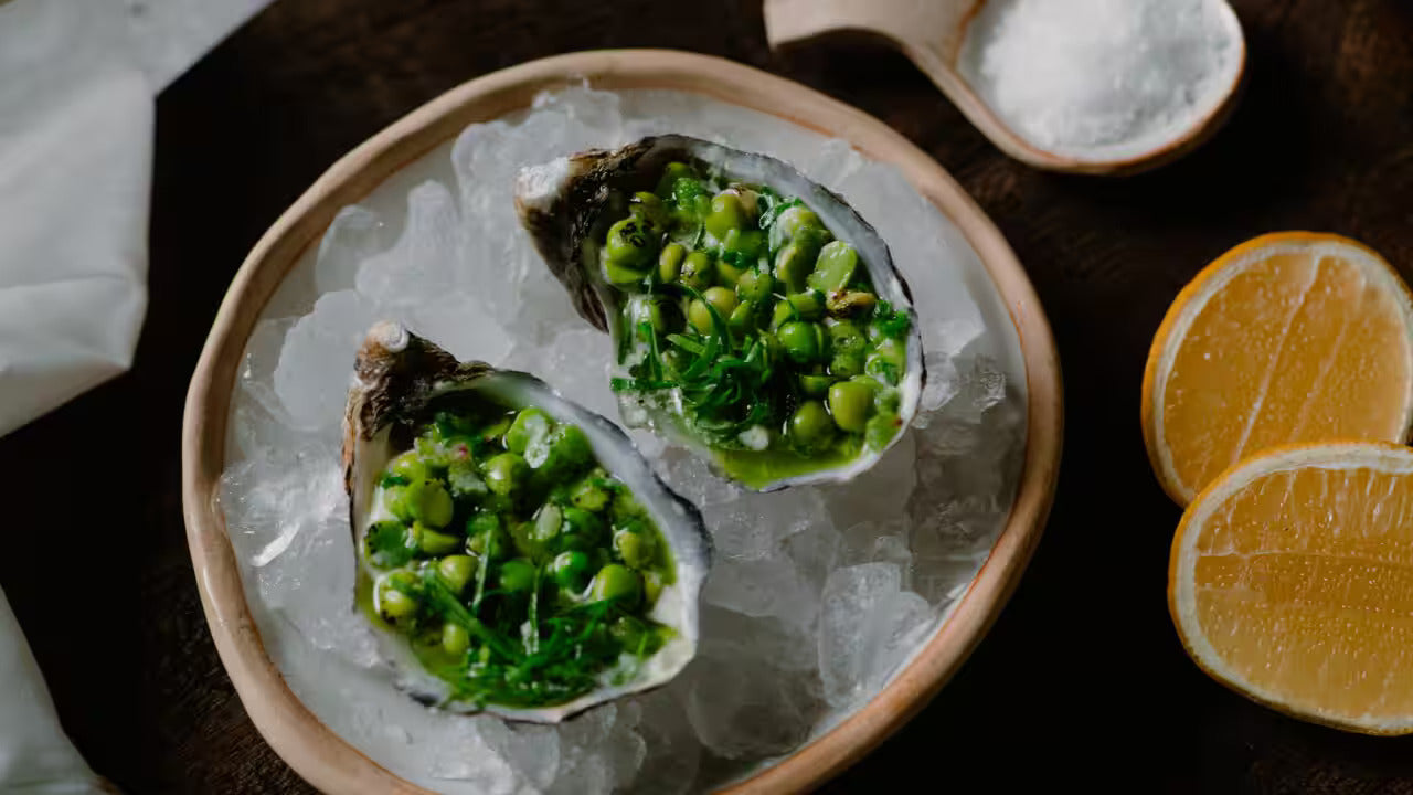 Pacific Oysters with Salted Cream & Charred Pea Salad displayed on ice.