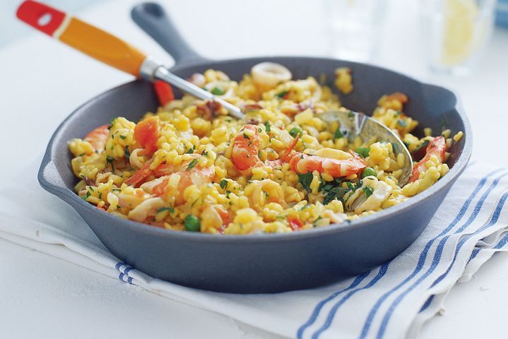 Saffron Risotto With Prawns And Squid in black pan.