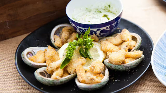 Sake Steamed Abalone With Liver Sauce displayed on a black plate.