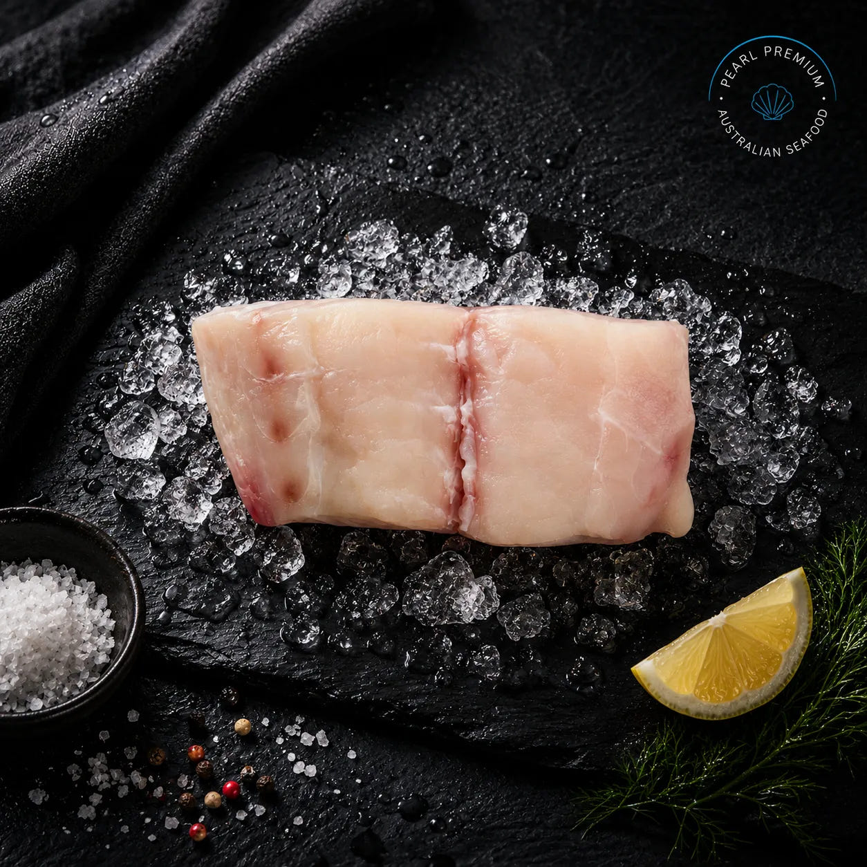 Fresh blue eye cod portions arranged on black slate over crushed ice with lemon