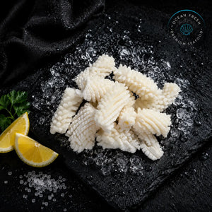 Frozen pineapple-cut squid pieces arranged on black slate with lemon