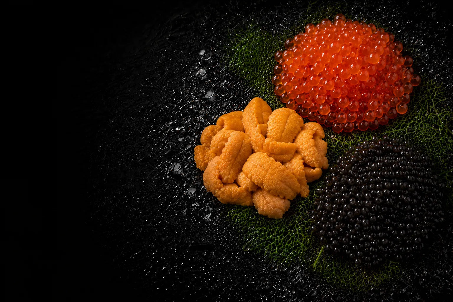 Two types of caviar, one red and one yellow, on a dark surface.