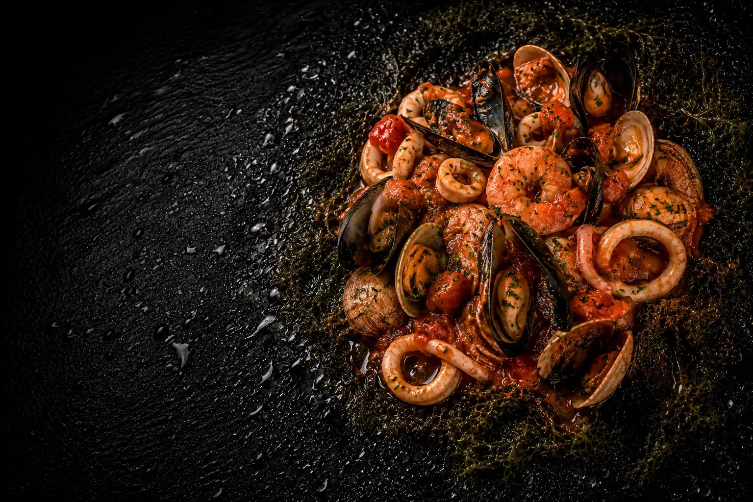 Seafood dish with shrimp, mussels, and calamari on a dark surface