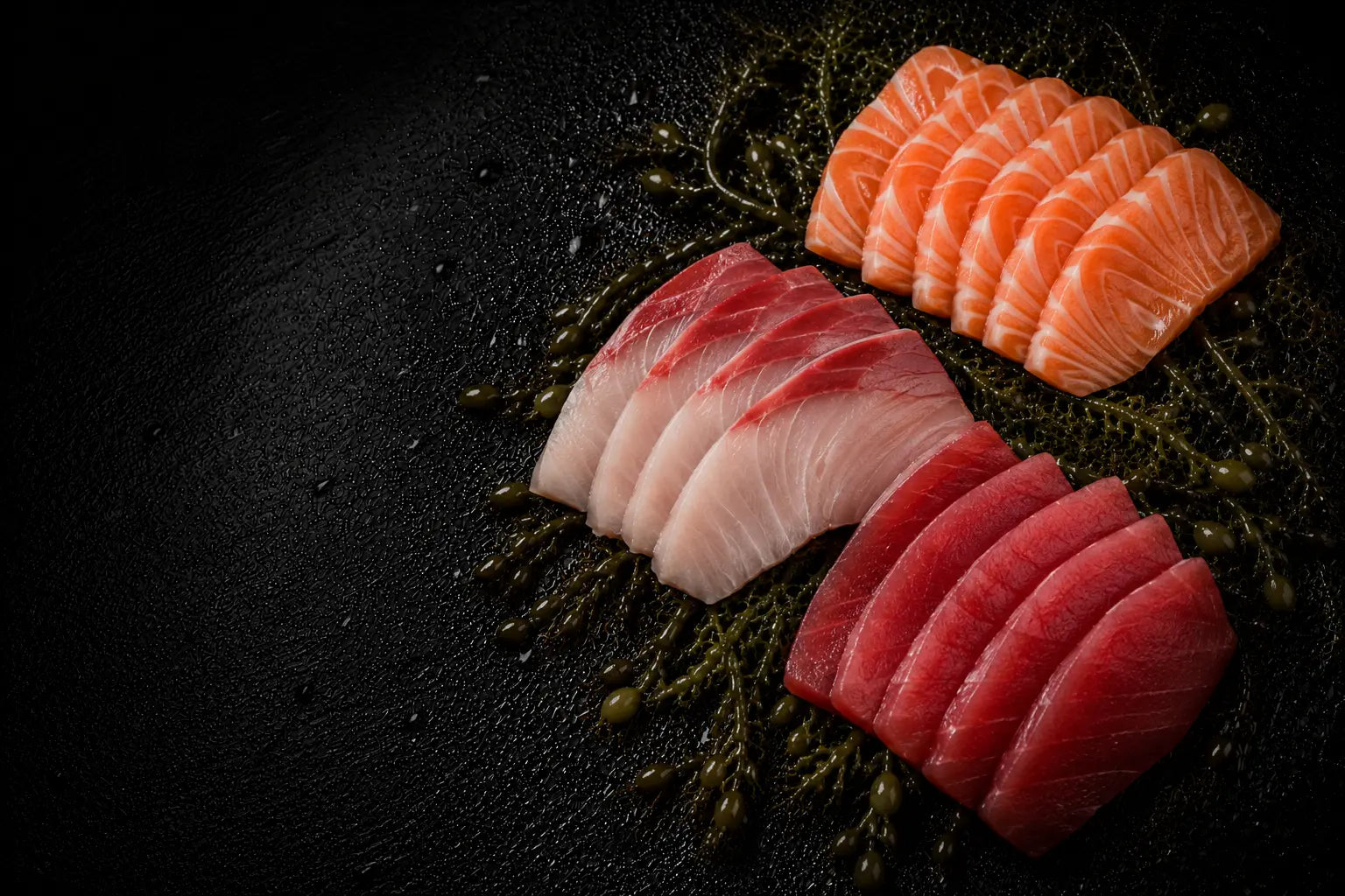 Sliced raw fish on a dark surface with garnishes