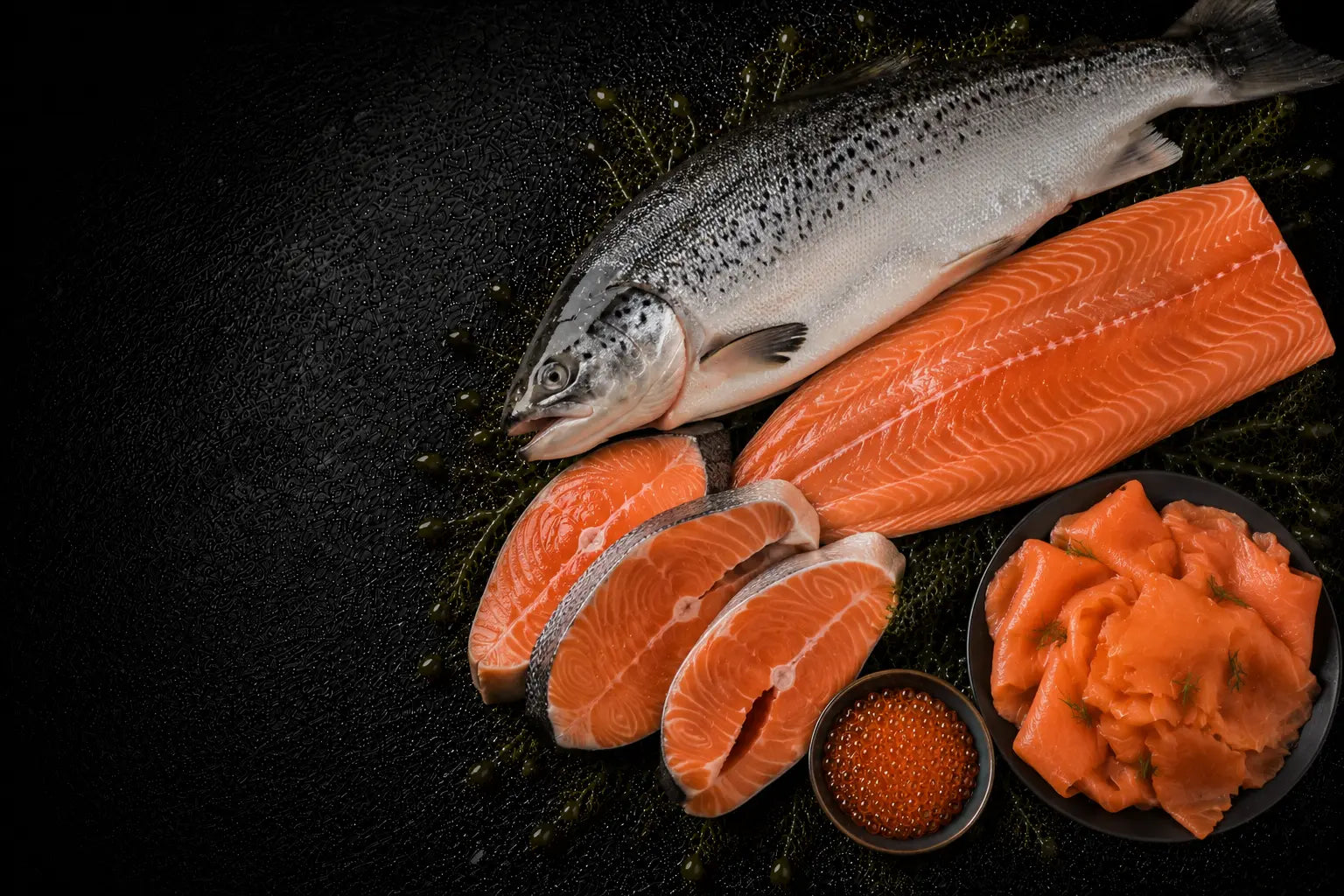 Salmon fillets and caviar on a dark surface