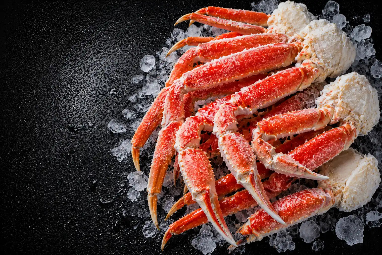Frozen crab legs on a bed of ice with a dark background