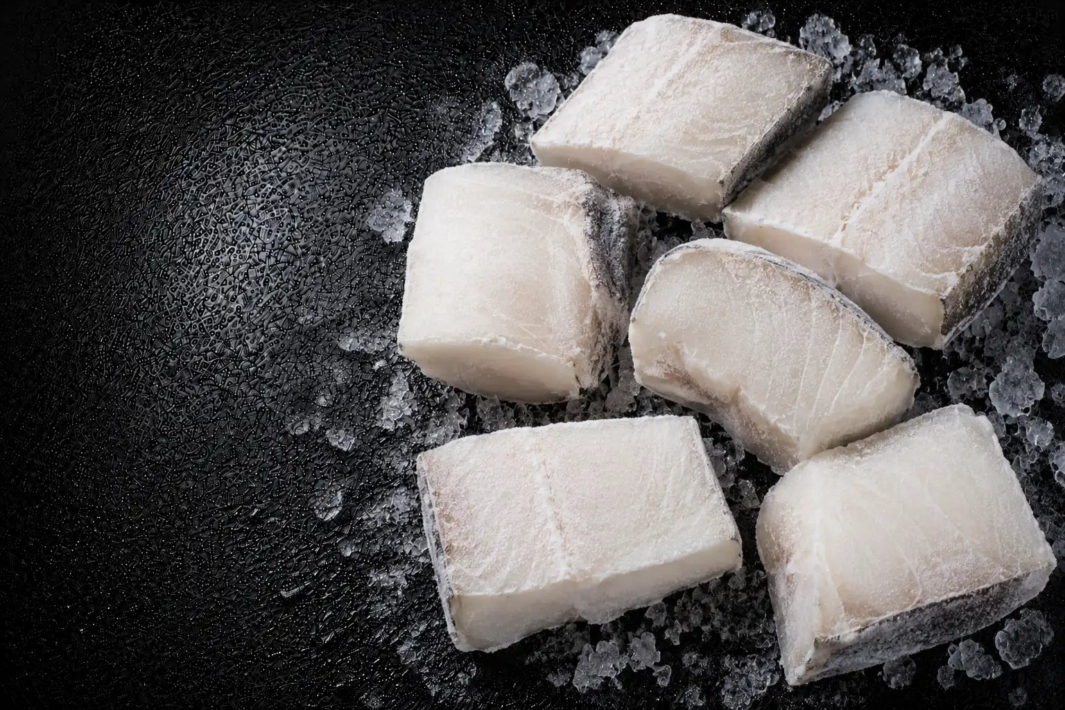 Raw fish fillets on a bed of ice with a dark background