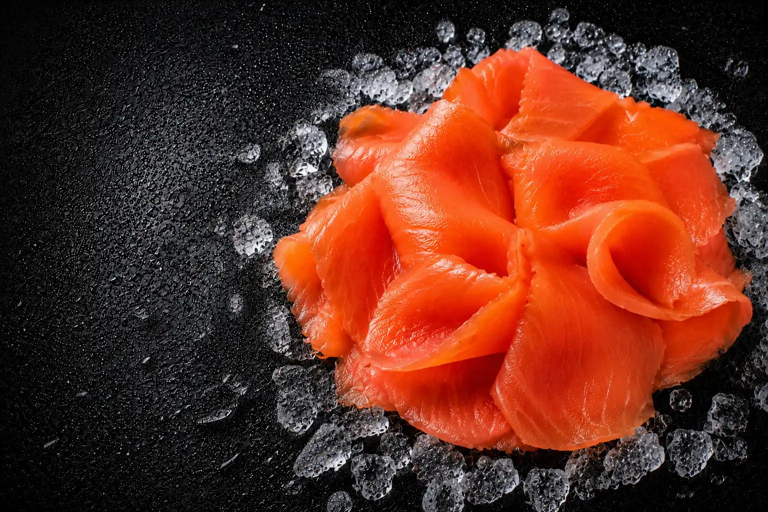 Salmon sashimi on a bed of ice with a dark background