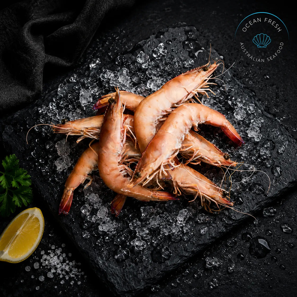 Frozen king prawns arranged on black slate with crushed ice and lemon