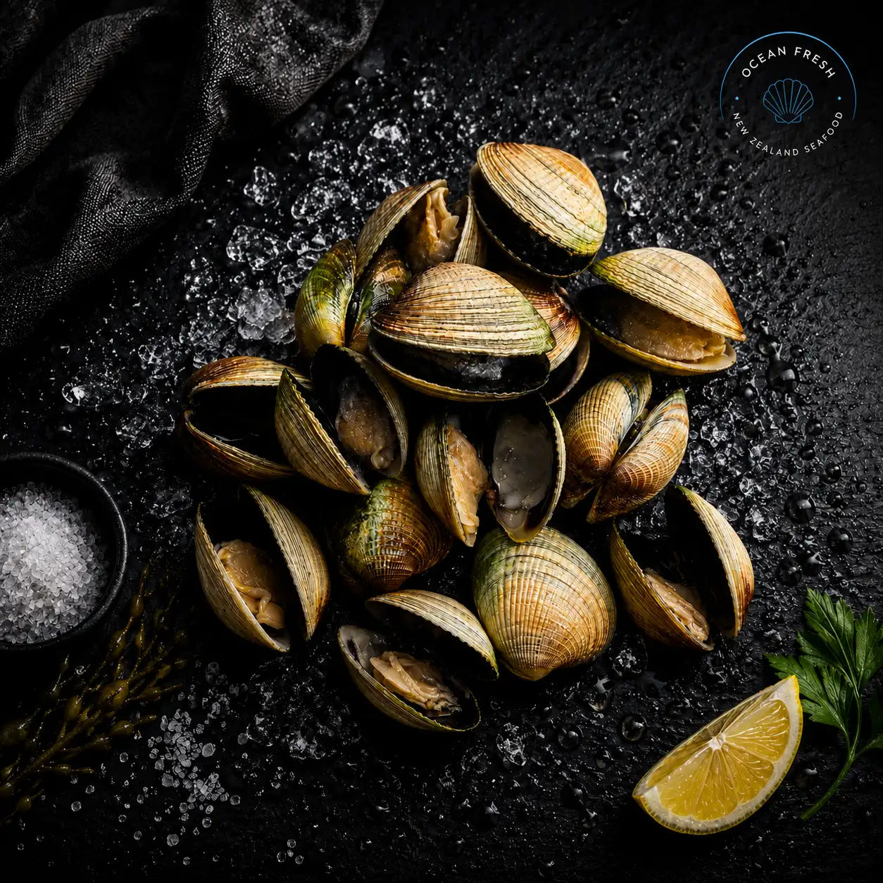 Frozen littleneck clams in their shells arranged on black slate with crushed ice and lemon