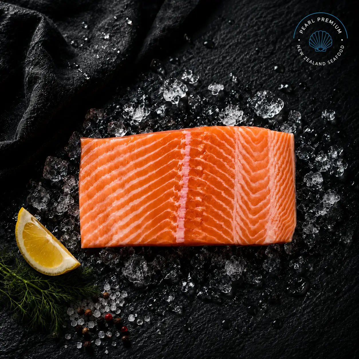 Fresh ora king salmon portions arranged on black slate over crushed ice with lemon