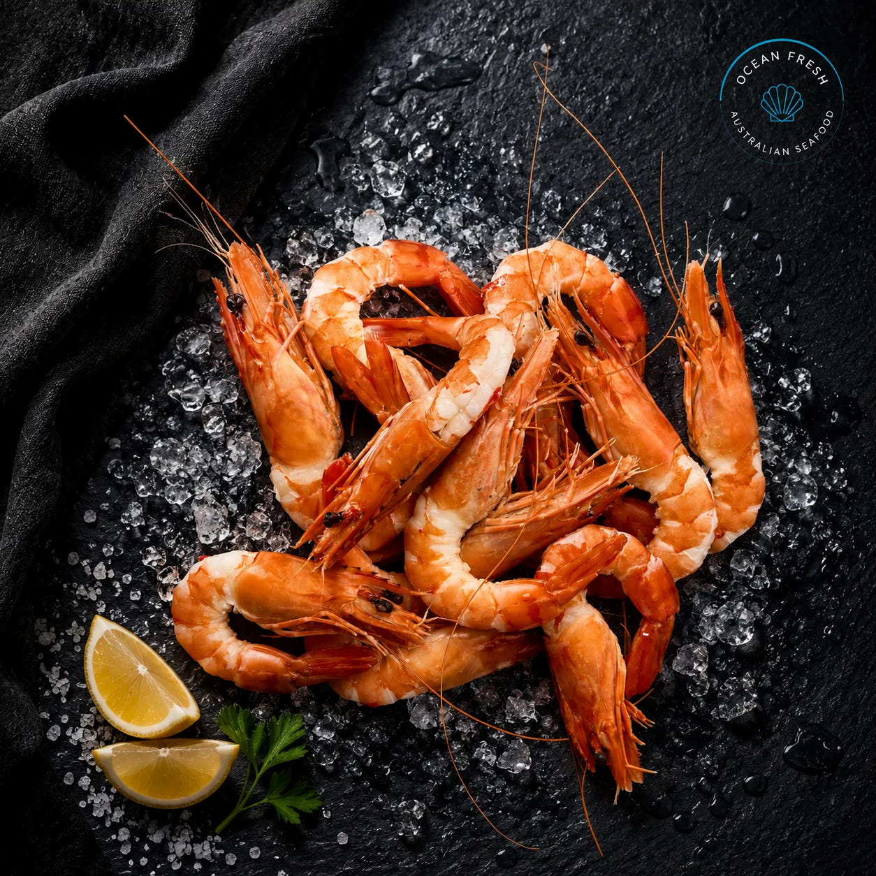 Fresh cooked head-on, tail-on tiger prawns arranged on black slate with crushed ice and lemon