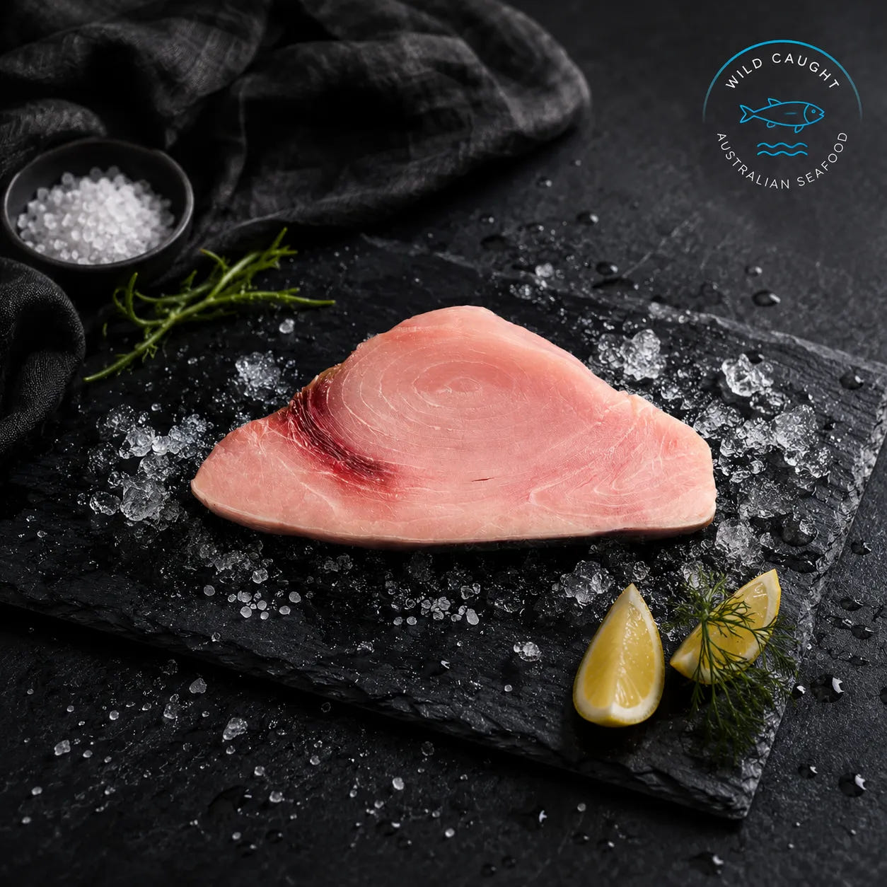 Fresh swordfish steak displayed on black slate over crushed ice with lemon