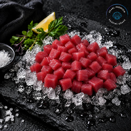 Diced raw tuna on crushed ice with a lemon wedge, parsley, and a small bowl of salt on a dark stone plate. A 'Pearl Premium Sashimi Grade' logo is visible in the top right corner.